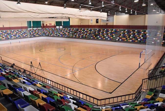 Interior del pabellón con pista de madera y gradas vacías listas para eventos