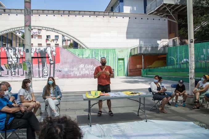 Evento comunitario en la Plaza Haundi con un ponente y público sentado
