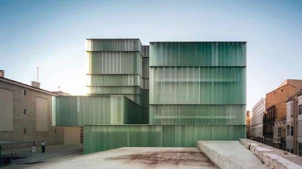 Ampliación moderna del teatro con estructura de vidrio verde translúcido