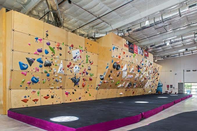 Pared de escalada de boulder con agarres coloridos y colchoneta de seguridad