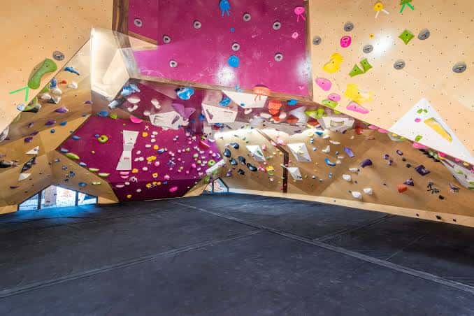 Detalle de una pared de escalada con formas irregulares y agarres multicolores