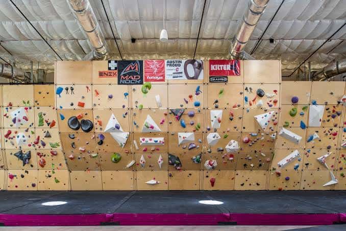 Pared de escalada con paneles modulares y logotipos de patrocinadores en la parte superior