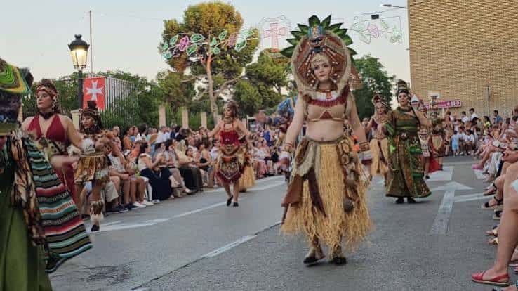 Desfile de danzas tradicionales con trajes coloridos en la calle durante la fiesta