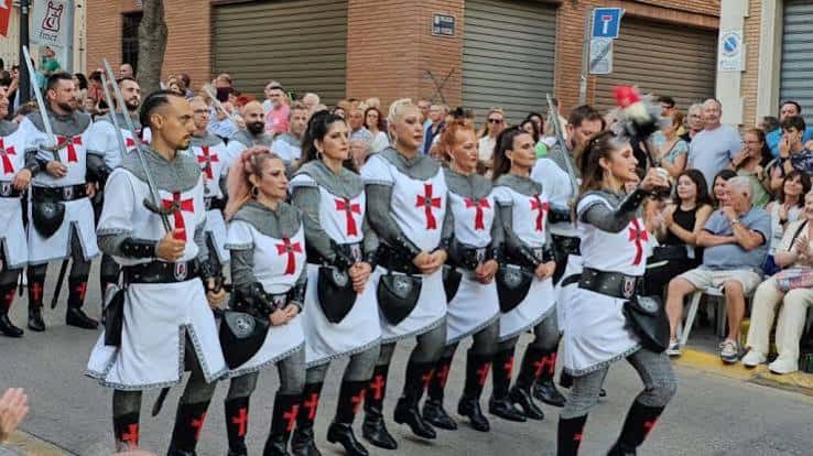 Grupo de participantes disfrazados de cruzados marchando en formación durante la entrada mora y cristiana