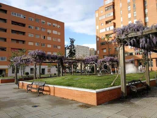Área ajardinada con pérgolas y edificios residenciales al fondo