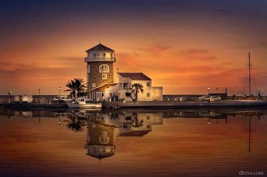 Torre del Puerto de Almerimar al atardecer con reflejo en el agua y embarcaciones cercanas