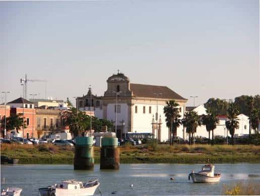 Vista panorámica del convento desde el río con embarcaciones y palmeras
