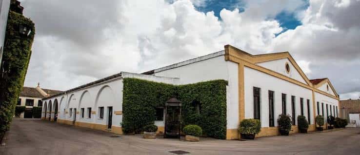 Vista panorámica de la fachada exterior de las bodegas con muros blancos y arcos