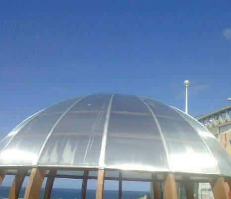 Primer plano de la cúpula metálica bajo un cielo azul despejado, destacando su forma semiesférica y diseño moderno