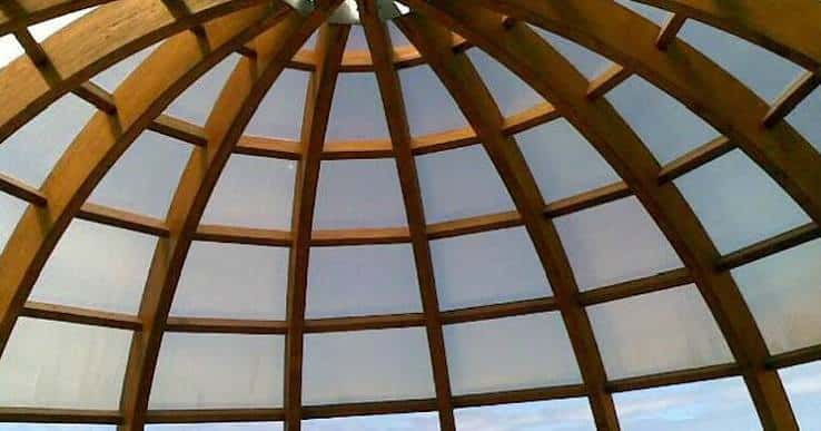 Interior de la cúpula desde abajo, mostrando la estructura de vigas de madera y paneles translúcidos que forman el techo