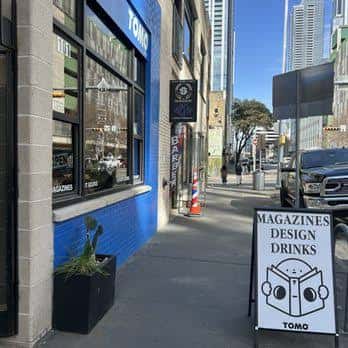 Vista exterior de la tienda TOMO MAGS en Austin con su distintiva fachada azul y letrero de 'MAGAZINES DESIGN DRINKS'