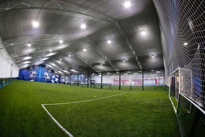 Campo de fútbol indoor con césped artificial y murales decorativos
