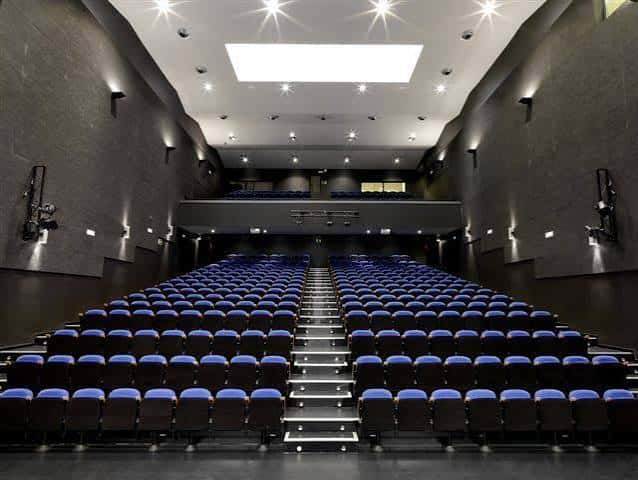 Interior del auditorio con butacas azules y escenario