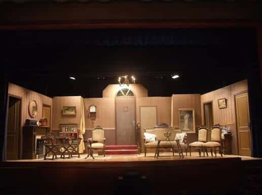 Escenario montado para obra de teatro con decoración de interior y mobiliario clásico
