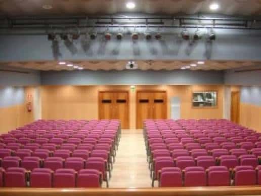 Plano frontal del auditorio con butacas dispuestas en gradas y puertas de acceso al fondo