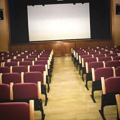Configuración del auditorio con pantalla de cine desplegada y butacas orientadas hacia el frente