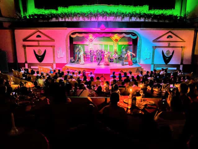 Interior del salón de eventos con público disfrutando de la función desde las mesas