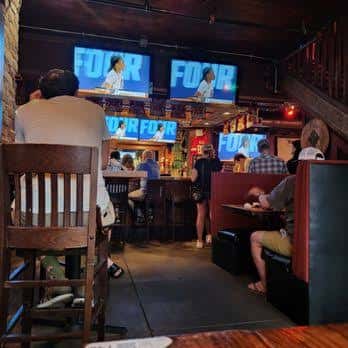 Interior del bar con clientes y pantallas de televisión