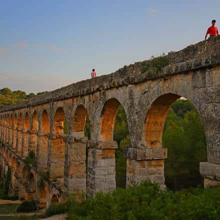Vista panorámica del Puente del Diablo al atardecer con visitantes en la parte superior