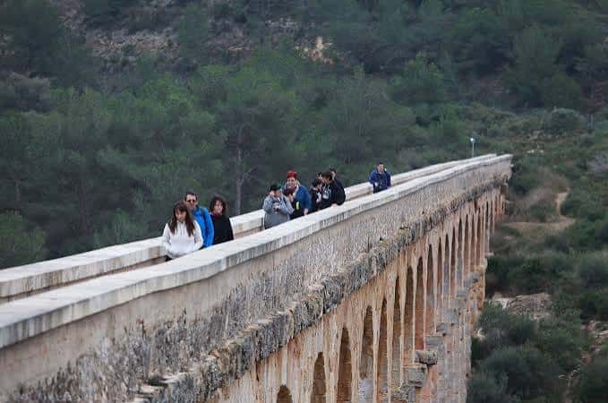Grupo de personas caminando sobre el acueducto romano en un día soleado