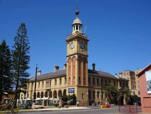 Vista exterior del edificio histórico con torre del reloj bajo un cielo azul
