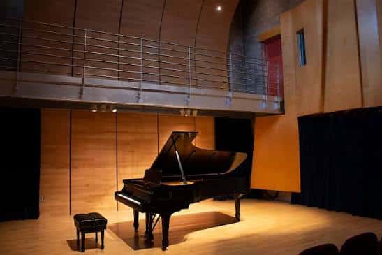 Piano de cola en el escenario del auditorio con iluminación cálida
