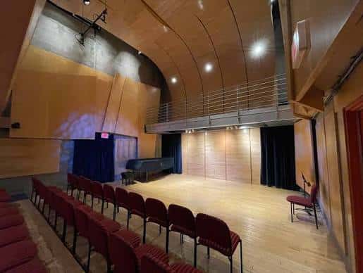 Escenario vacío con piano y cortinas azules en el fondo