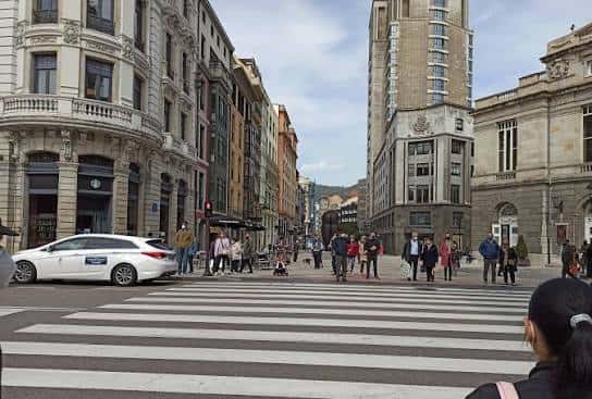 Vista diurna de la Calle Pelayo en Oviedo con edificios históricos y peatones cruzando