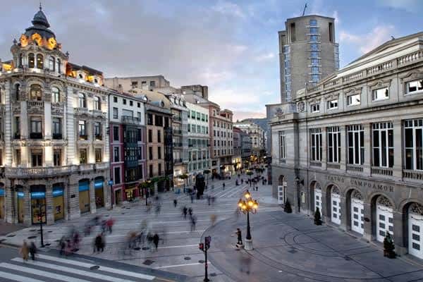 Vista panorámica de la Calle Pelayo al atardecer con el Teatro Campoamor iluminado