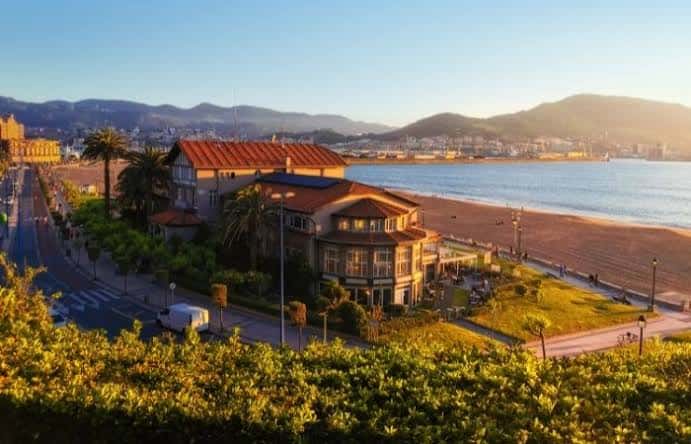 Vista de la Playa de Ereaga al atardecer con edificios y palmeras