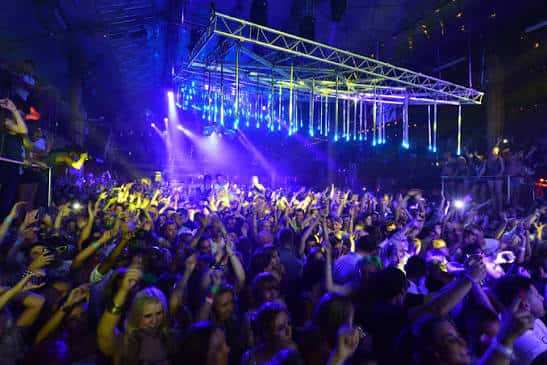Escena nocturna en Amnesia Ibiza con luces azules, escenario elevado y multitud con manos en alto