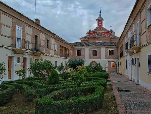 Jardín interior con setos geométricos y la cúpula de la iglesia al fondo