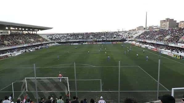 Partido en desarrollo en el campo de fútbol con espectadores en las gradas