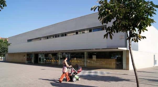Vista exterior de la Biblioteca Ernest Lluch en Girona con una persona paseando