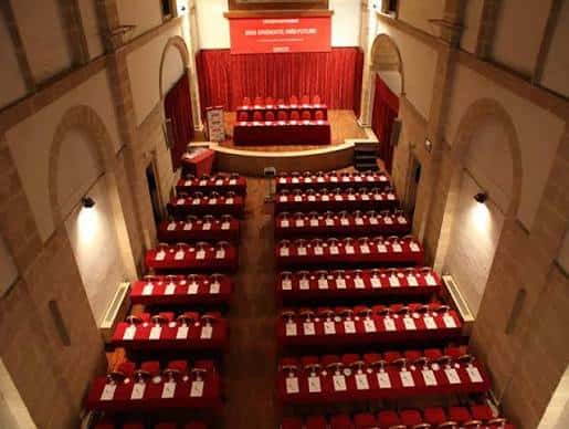 Interior del monasterio configurado como sala de eventos con mesas y sillas rojas