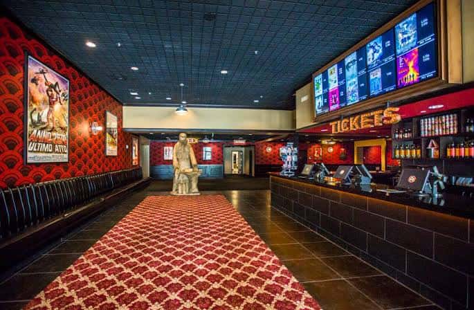 Interior del vestíbulo con mostrador de taquilla, alfombra roja y decoración temática