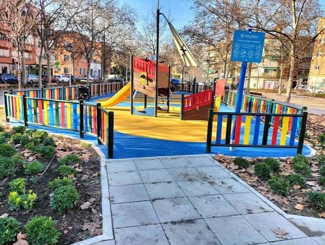 Vista general del área de juegos infantil con estructura de barco pirata y suelo de caucho multicolor