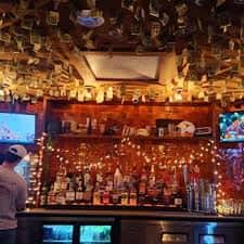 Interior del bar con estanterías llenas de botellas y luces decorativas