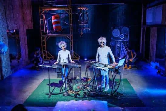Escenario de Crashbox con dos artistas tocando teclados bajo luces azules