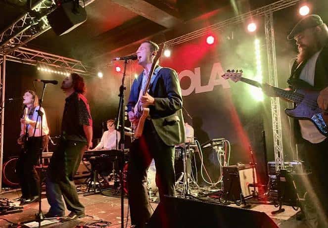 Concierto en vivo en el KOLA Portsmouth con banda actuando bajo luces de escenario