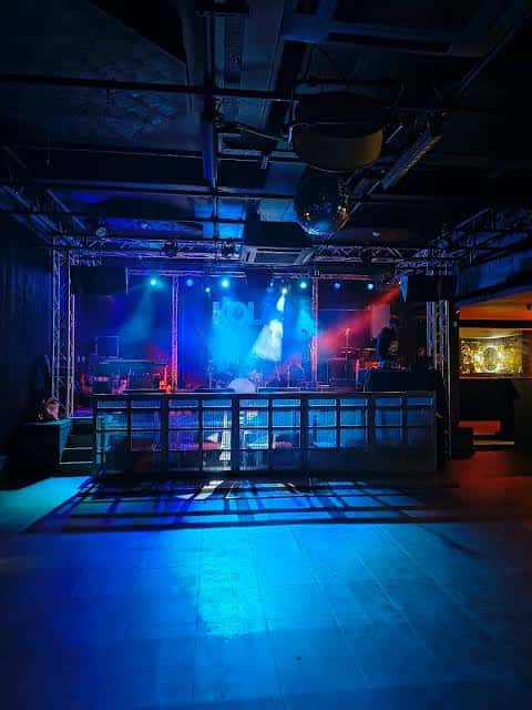 Vista del escenario vacío del KOLA en Portsmouth con iluminación azul y ambiente de sala de conciertos