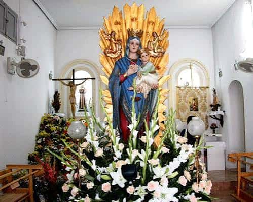 Estatua de la Virgen de Santa Marta con corona dorada y flores en el altar