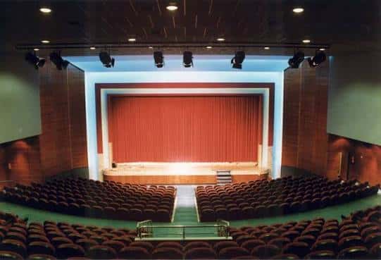 Interior del auditorio con butacas rojas y pantalla de cine