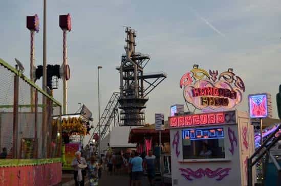 Calle del recinto ferial con atracciones y la torre industrial al fondo
