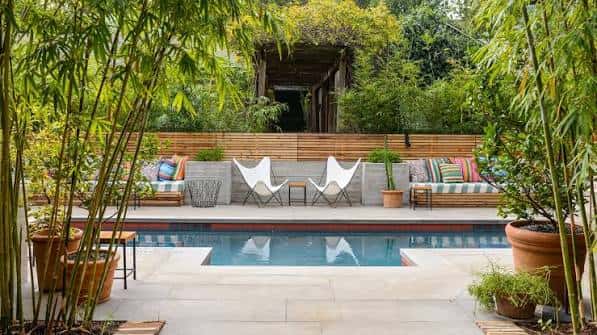 Piscina privada rodeada de vegetación exuberante y mobiliario de diseño
