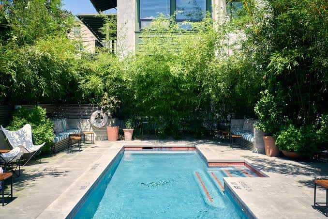 Vista amplia de la piscina con jardines tropicales y zona de descanso