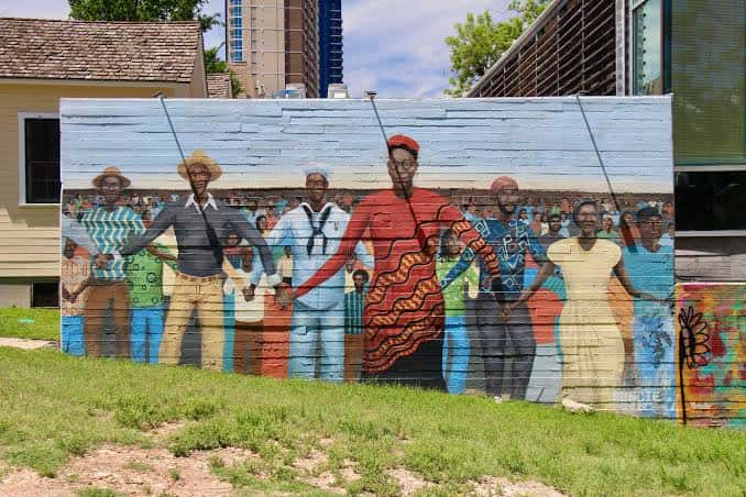 Mural vibrante en la fachada exterior que representa figuras históricas afroamericanas