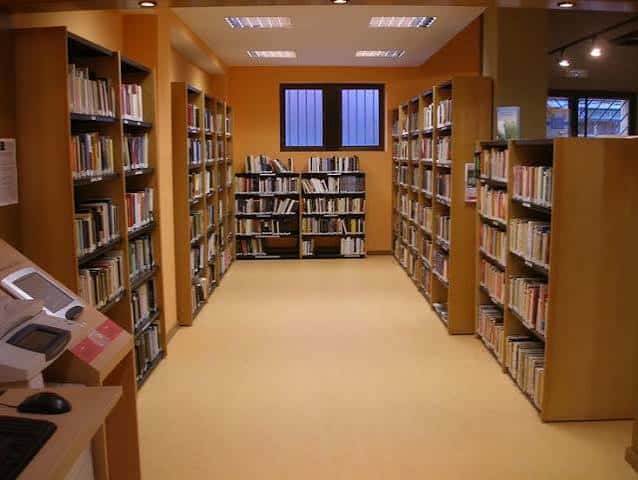 Pasillo interior de la biblioteca con estanterías de madera y libros organizados