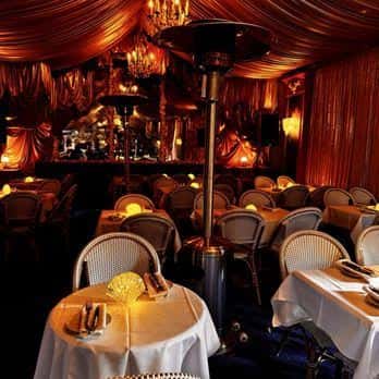 Sala de eventos decorada con cortinas rojas y mesas preparadas