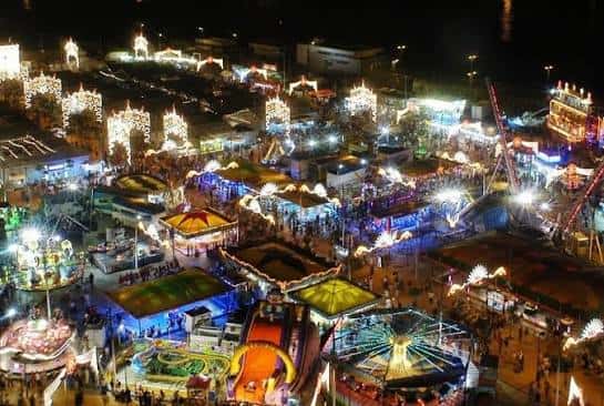 Vista aérea nocturna del recinto ferial con casetas iluminadas y atracciones
